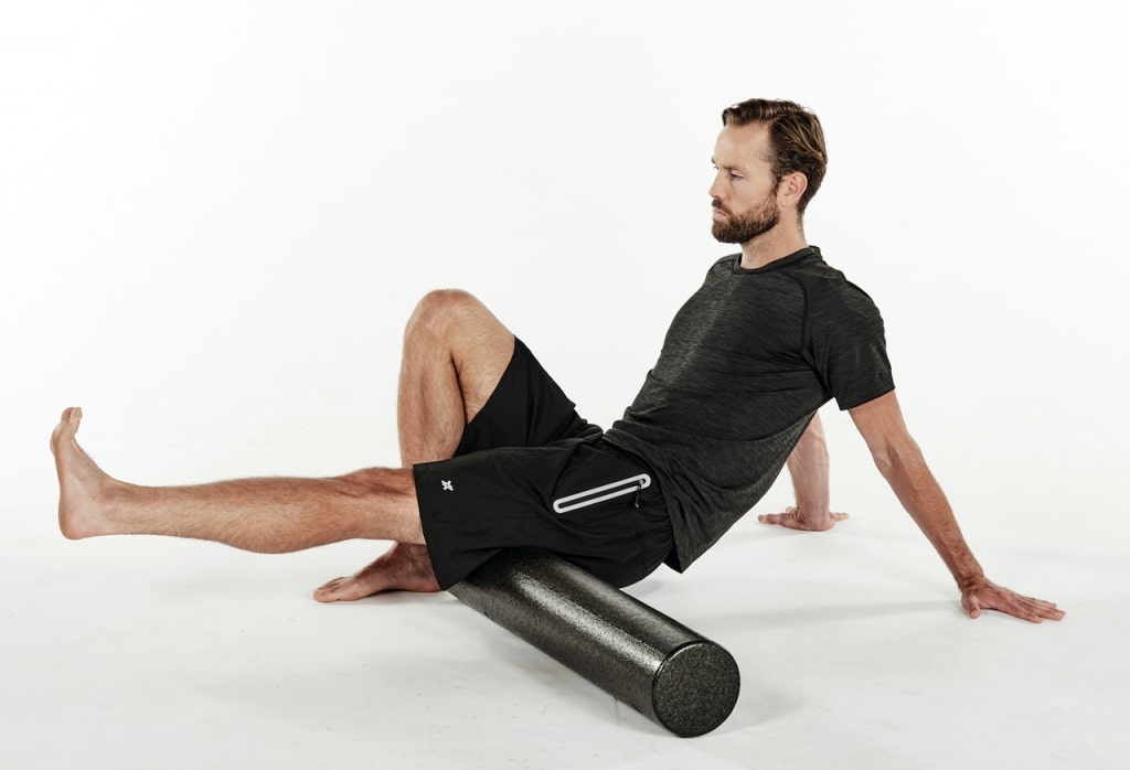 man working on hamstrings with a foam roller