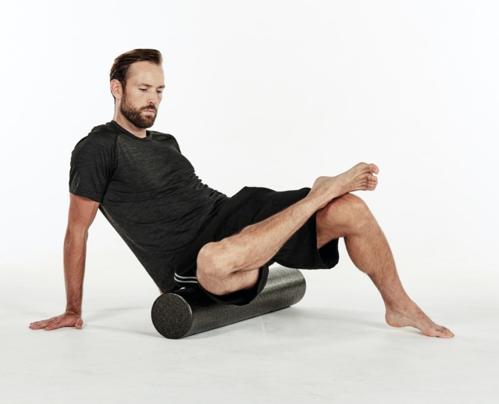 man giving glutes a massage with a foam roller