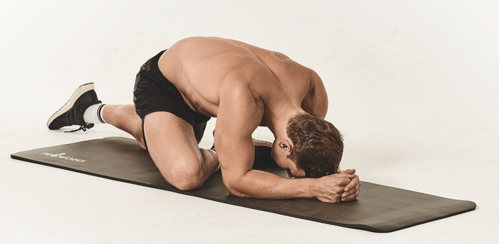 man demonstrates pigeon pose on yoga mat
