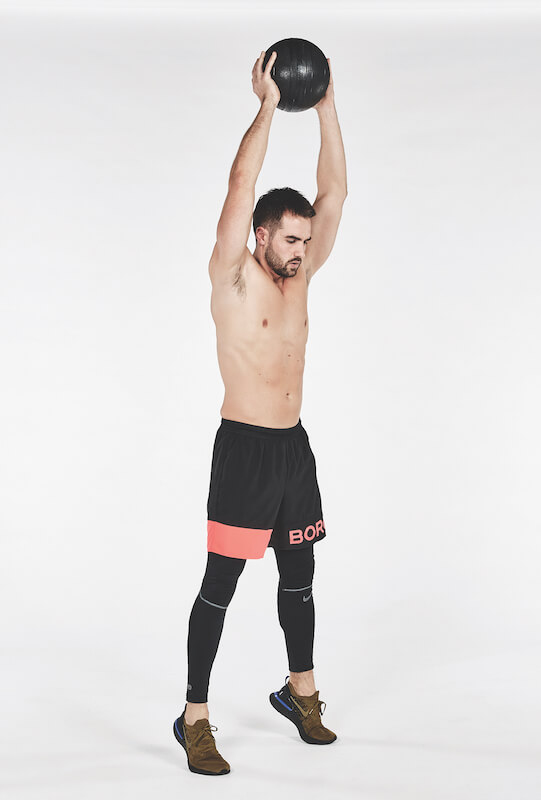 Topless man performing one of the best workout finishers, the medicine ball slam against white background