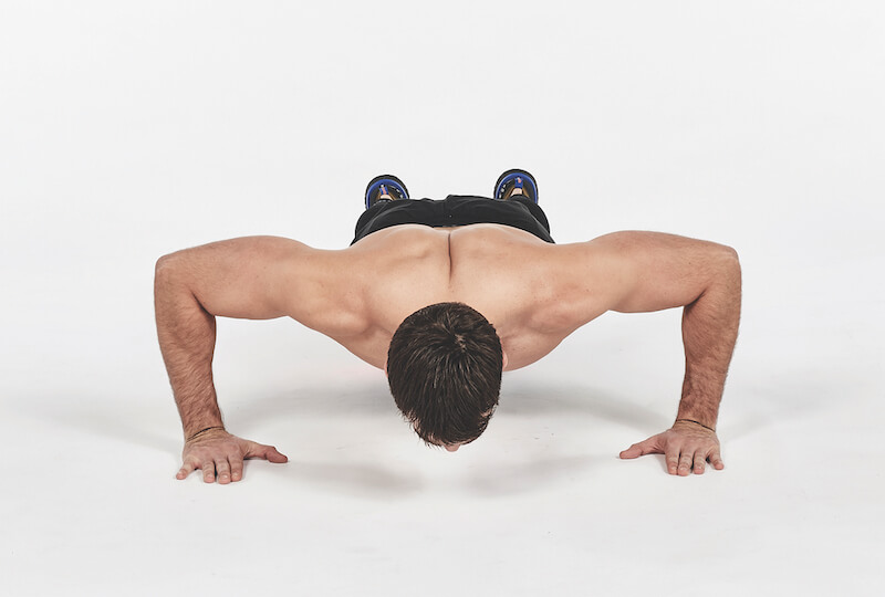 man demonstrates how to do push up exercise with wide arms, one of the best workout finishers