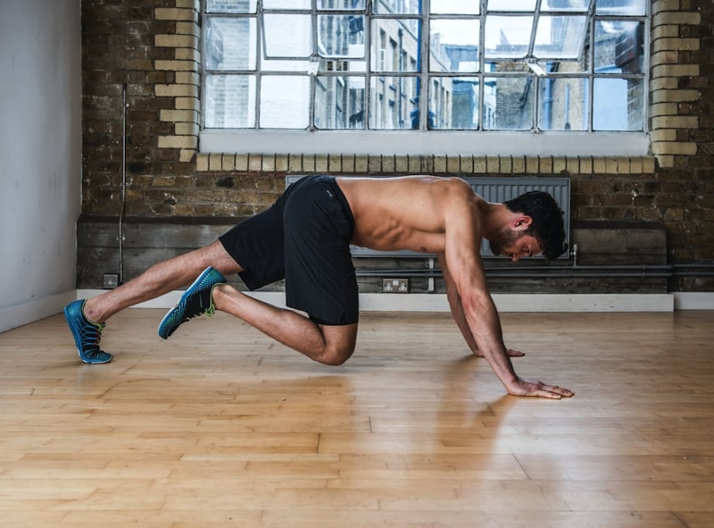 Man performing single-leg knee drive – one of the best plank variations