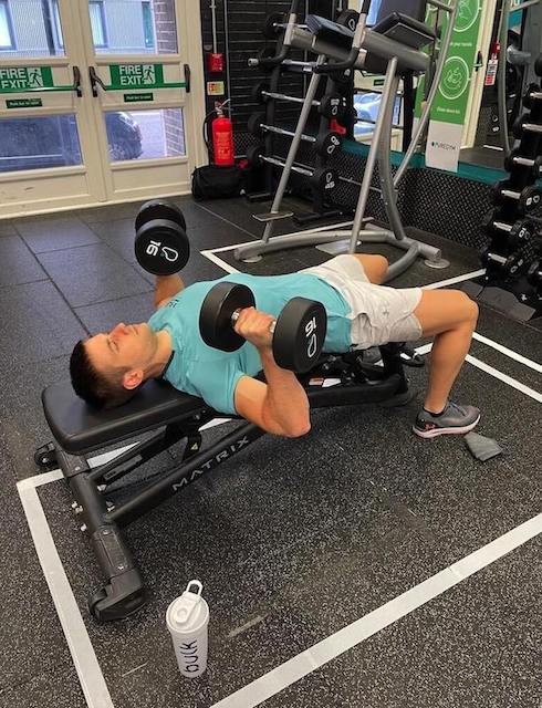 man in gym performing dumbbell chest press as part of a 30-minute upper-body workout