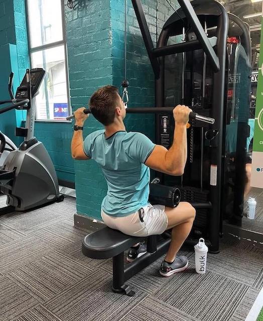 man in gym performing lat pull-down as part of a 30-minute upper-body workout