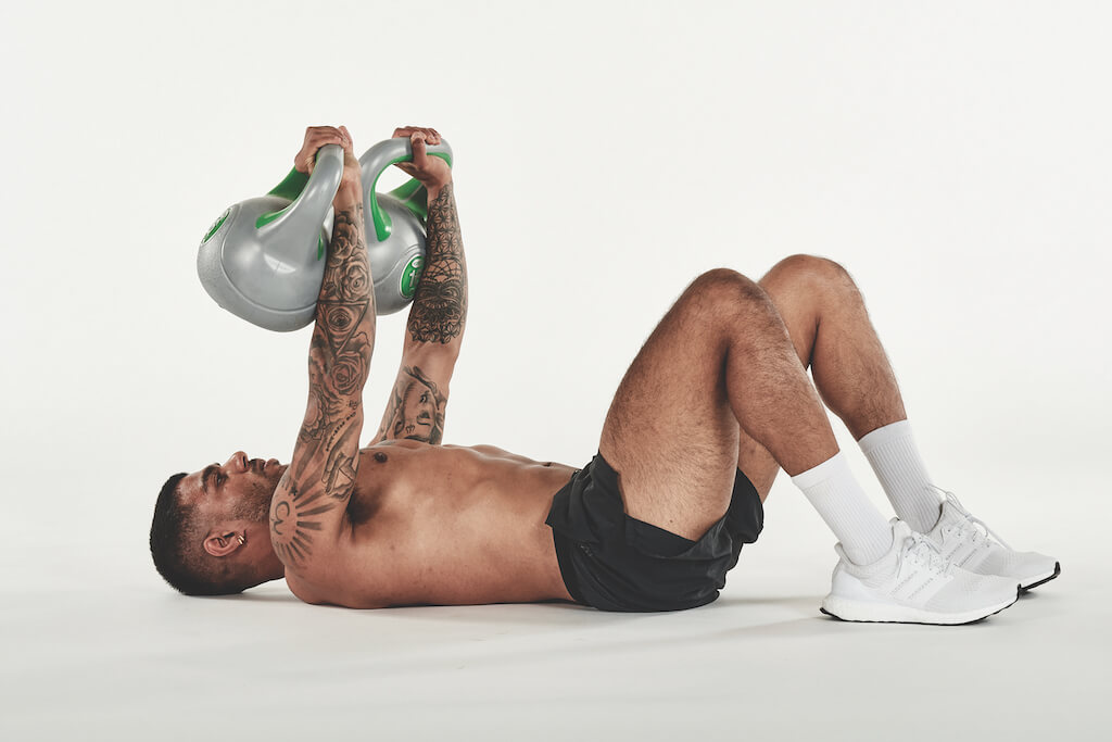 topless man demonstrating how to do a kettlebell floor press as part of a full-body kettlebell workout