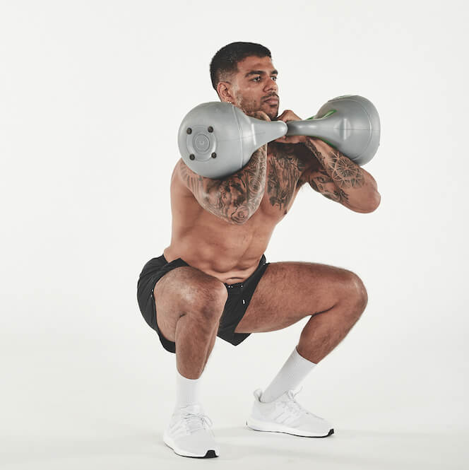 topless man demonstrating how to do a kettlebell front squat as part of a full-body kettlebell workout