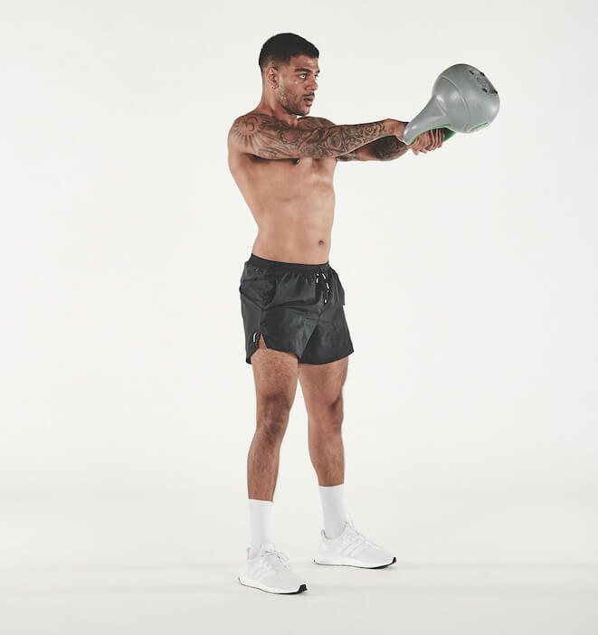 topless man demonstrating how to do a kettlebell swing