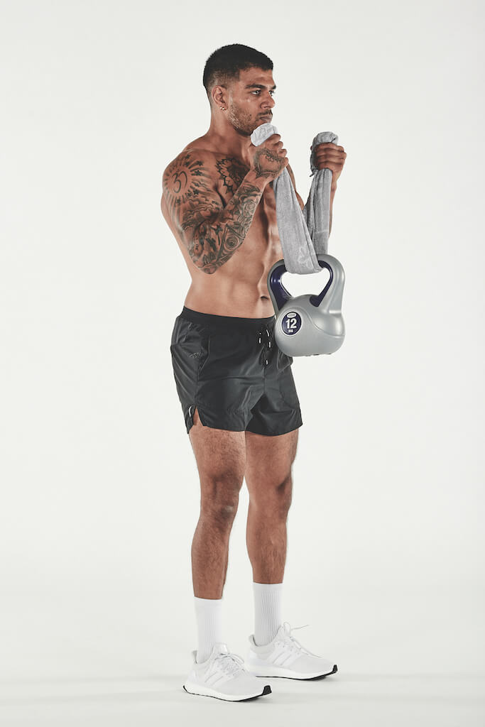 topless man demonstrating how to do a kettlebell towel curl