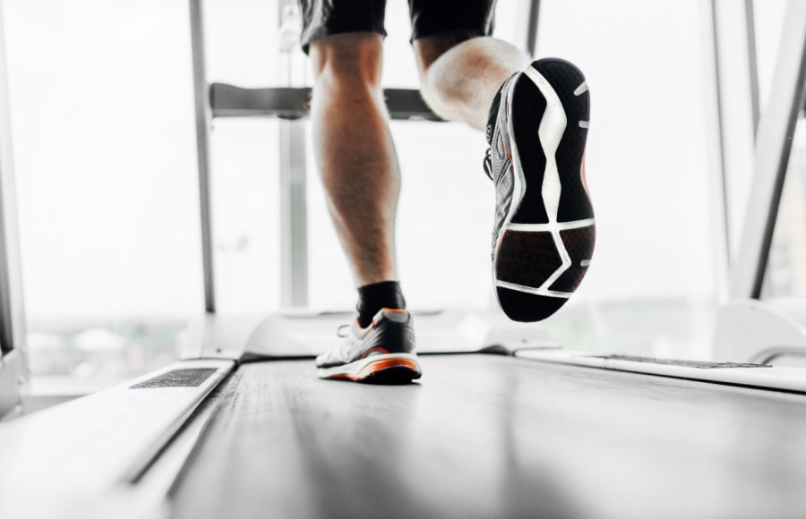 man wearing gym trainers while running on treadmill