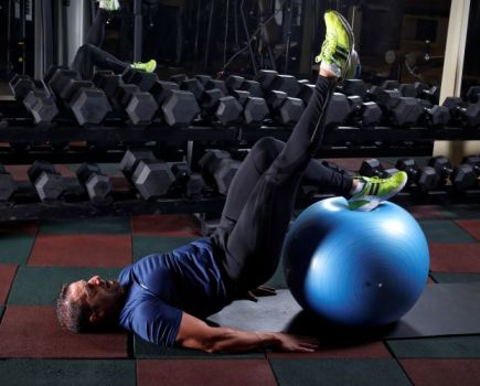 Man in a gym performing Swiss ball exercises