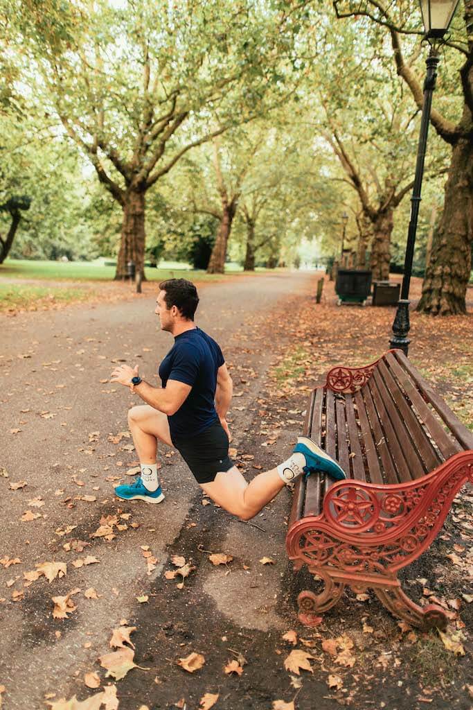 man performs split squat using park bench