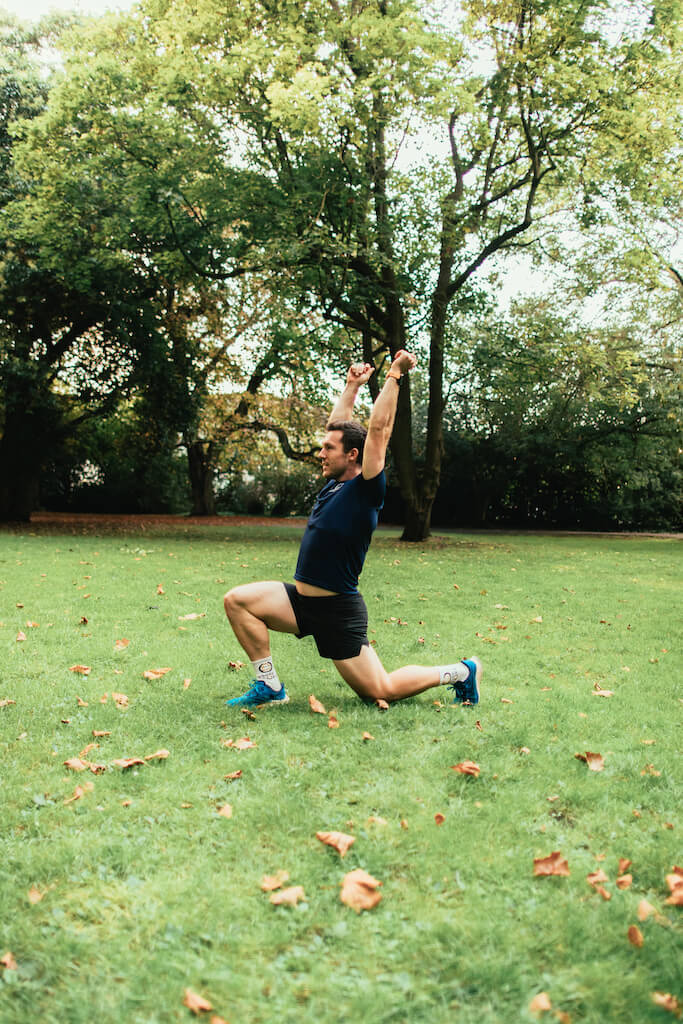 man demonstrates lunge and reach in bodyweight workout for runners