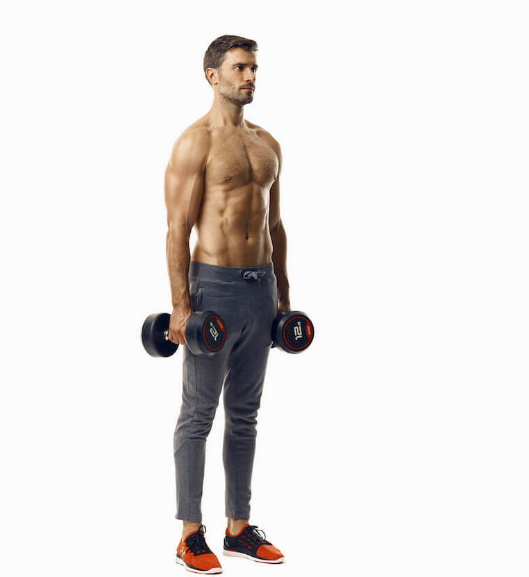 man demonstrates step one of dumbbell hammer curl; standing upright, he holds a dumbbell in each hand by his sides in home dumbbell hiit workout