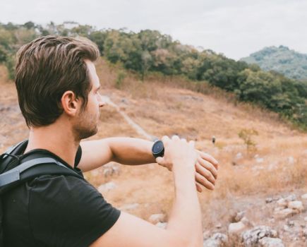 man using fitness watch to track outdoor hike