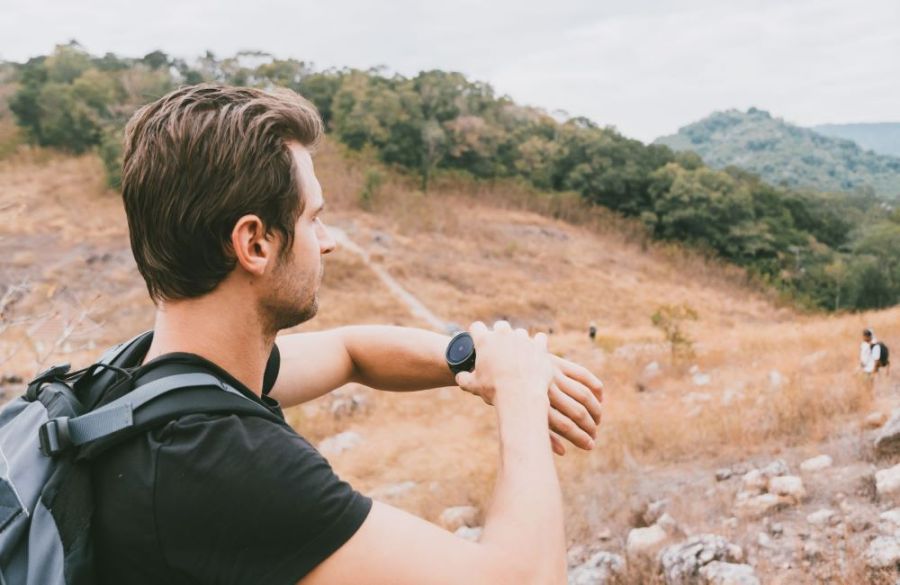 man using fitness watch to track outdoor hike