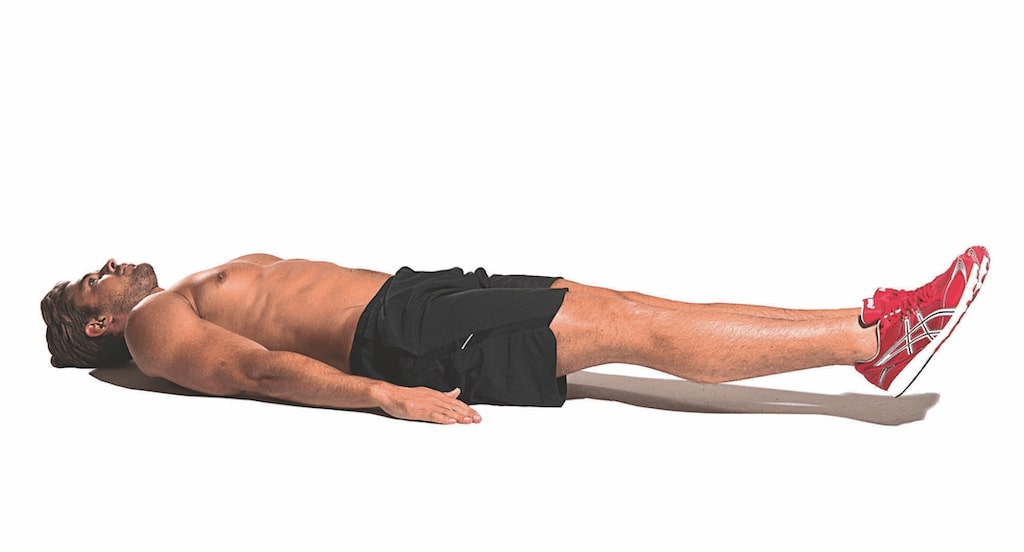 man lying flat on ground demonstrating part one of modified v-sit