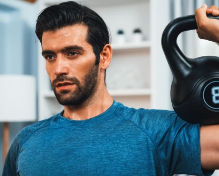 man working out with a kettlebell wearing a blue top