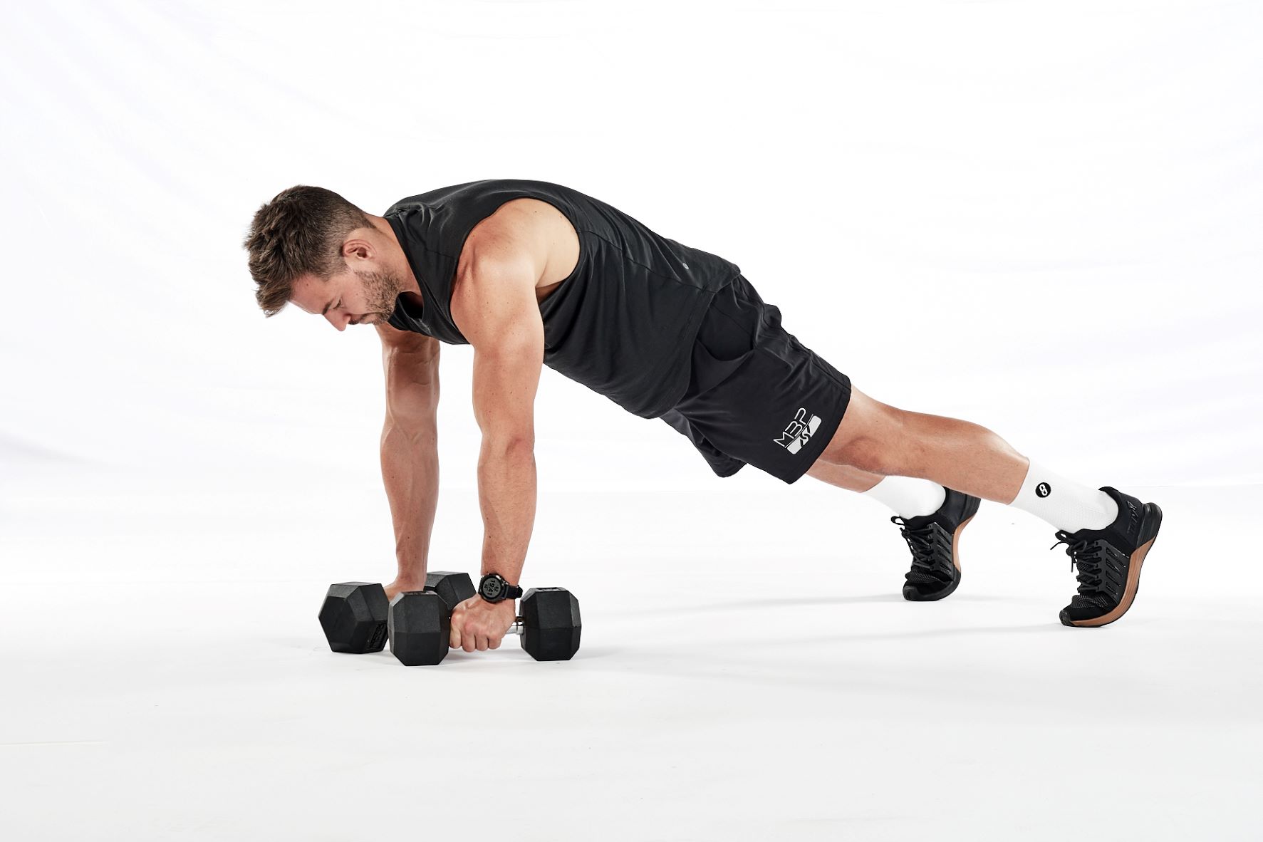 Three stages of the dumbbell renegade row – in a press-up position, holding a dumbbell in each hand; rowing up towards the hip with one hand; rowing up towards the hip with the other.