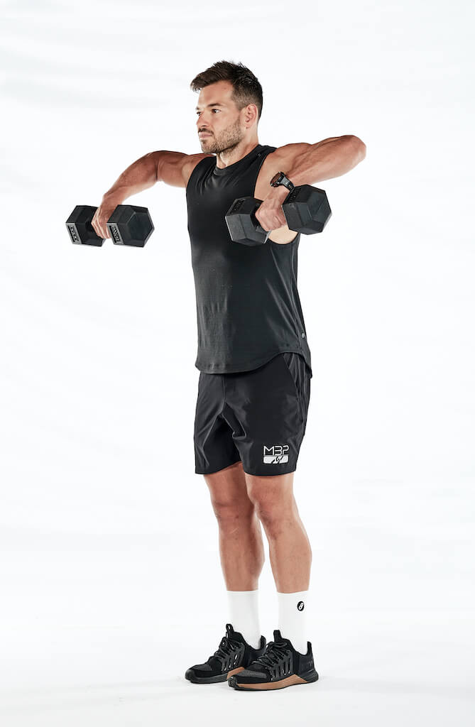 Two stages to the shrug – standing, holding weights by the hips; then shrugging the shoulders to lift weights up towards armpits.