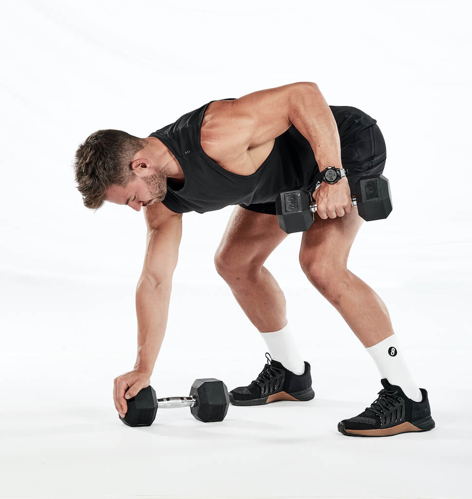 Two stages of the single-arm dumbbell gorilla row – hinging forward at the hips, knees slightly bent to grasp a dumbbell on the floor; keeping this position pulling the weight up towards the hip.