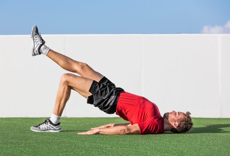 How to build leg muscles - man lying on his back performing a single leg glute bridge