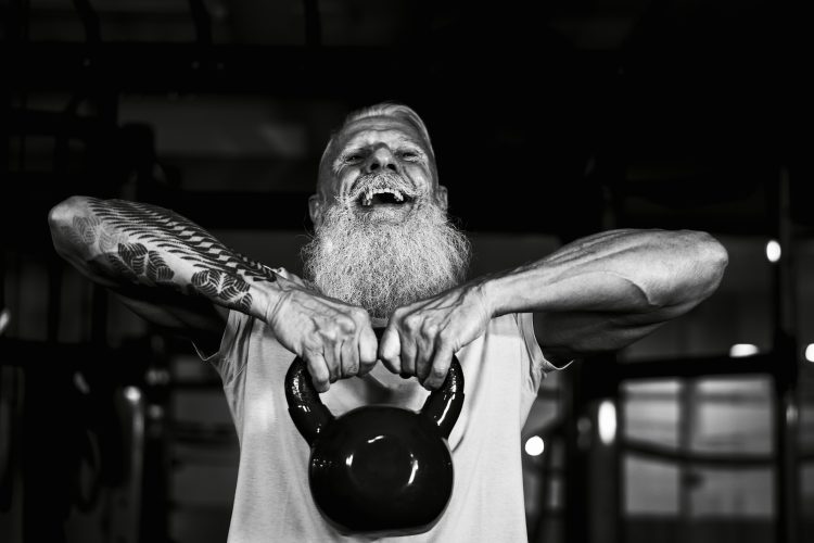An old man with white hair and beard lifting a kettlebell