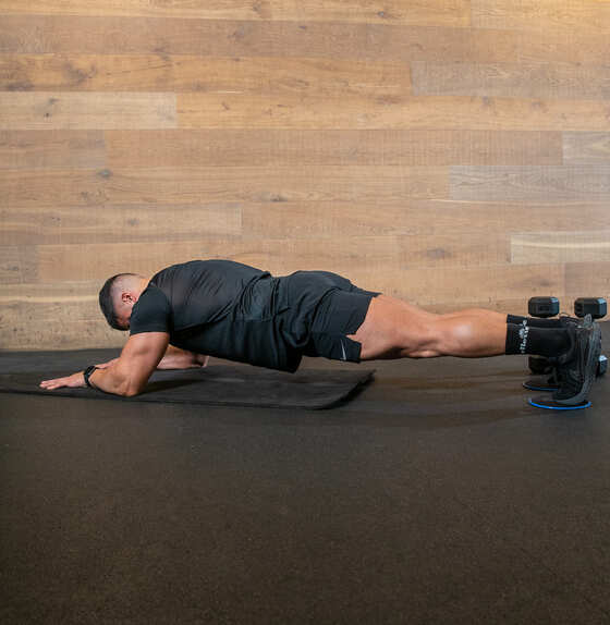 man slides himself back and forwards in low plank position