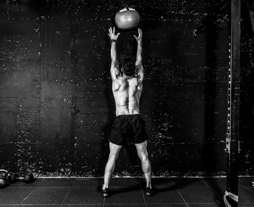man performing wall ball CrossFit exercise with back to camera
