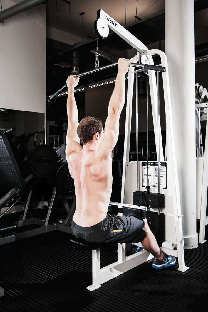 man demonstrates lat pull down in the gym to build bigger back muscles