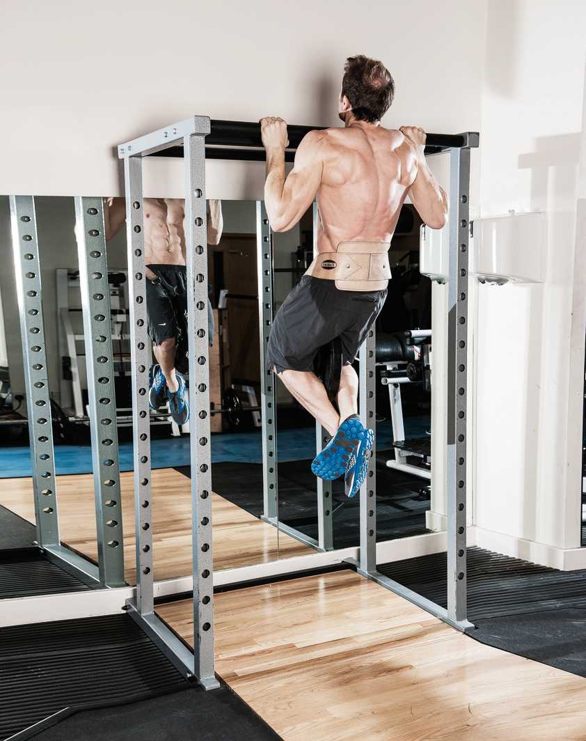 man demonstrates weighted pull up in gym