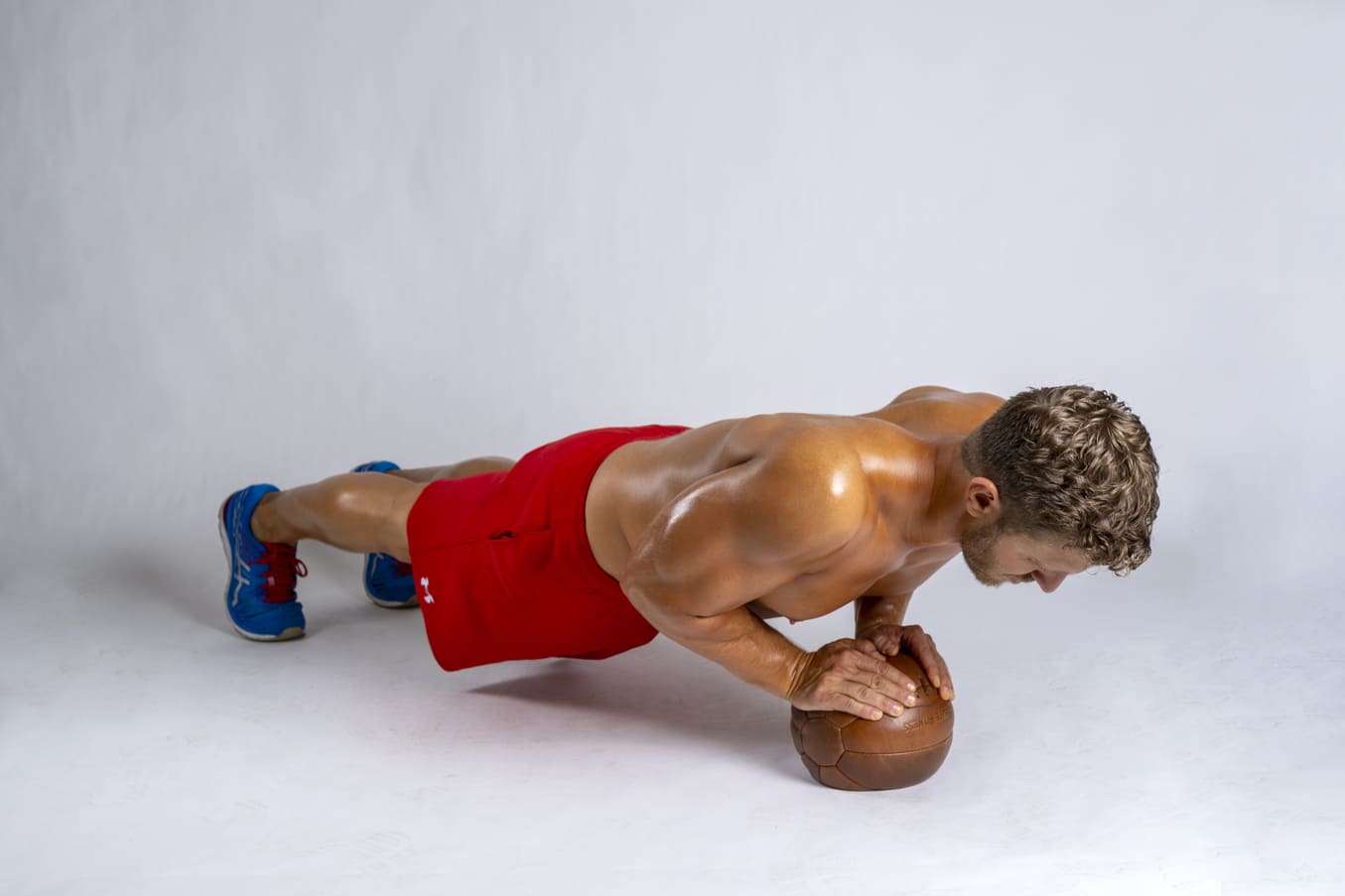 man performs medicine ball push ups in dumbbell superset arm workout