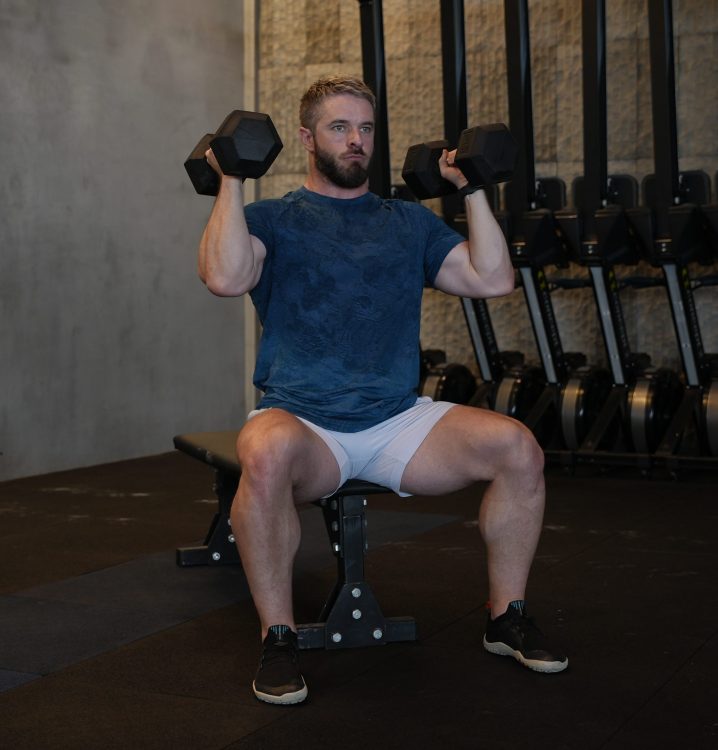 Man performing seated dumbbell shoulder press - best shoulder press variations