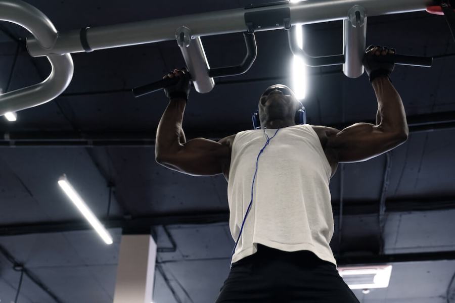 man performing pull up exercise in gym