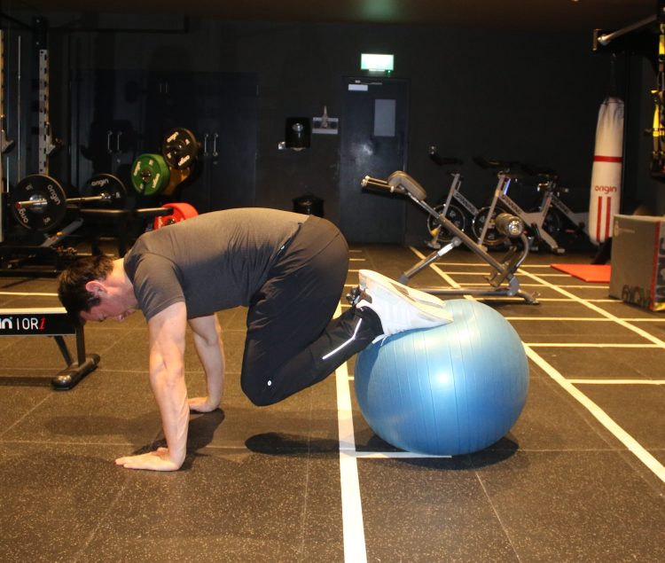 Man performing end of gym ball frog exercise