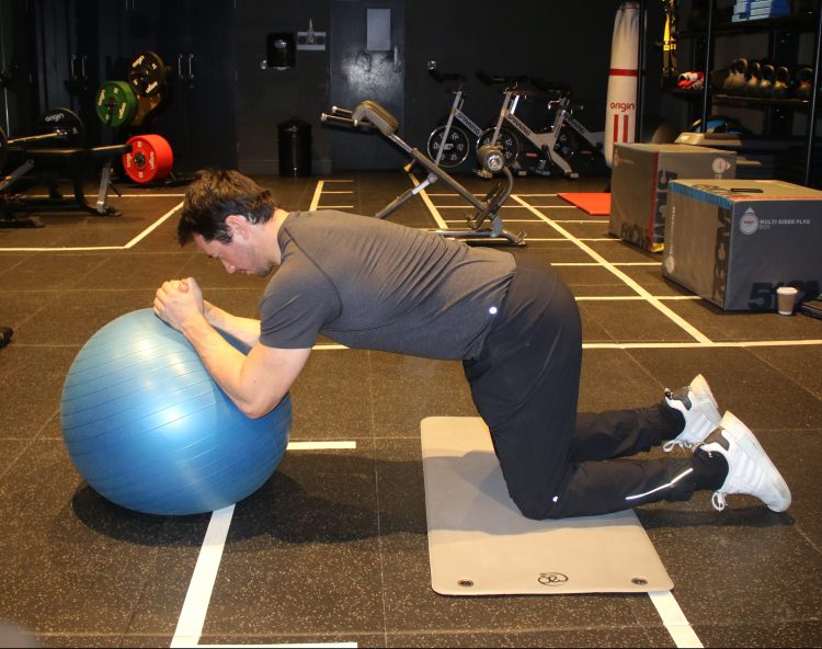Man performing a gym ball rollout - best lower abs exercises