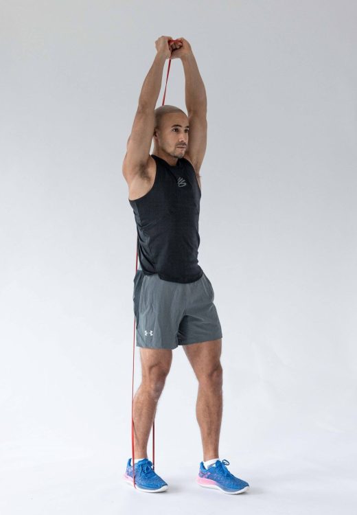 Man performing end of a banded overhead triceps extension - resistance band arm exercises