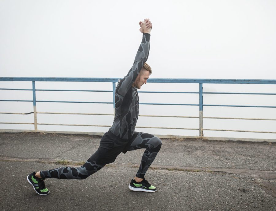 Athletic man in compression clothing stretches on a bridge before running
