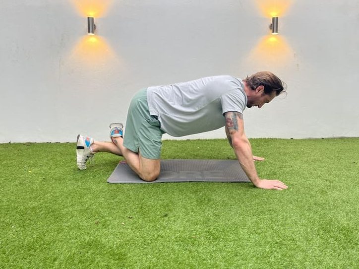 man demonstrating how to do all fours glute mobilisation stretch