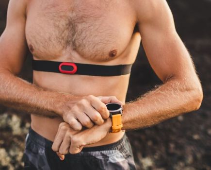 Upper torso of a man wearing a heart rate monitor and checking his watch