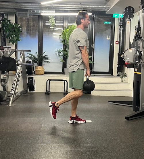 Man performing single-leg Romanian deadlift with kettlebell – one of the best glutes exercises