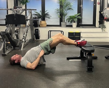Man performing frogger glutes exercise in gym