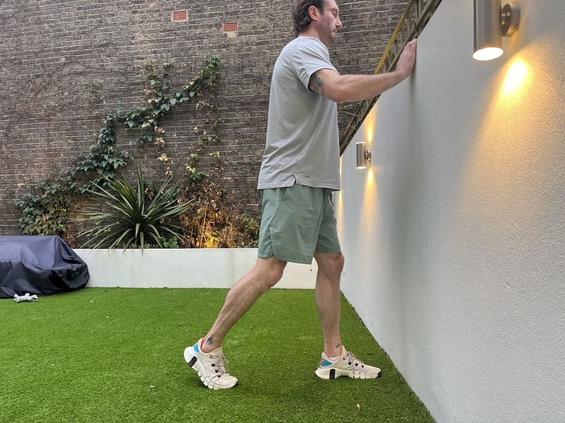 man demonstrates how to do kneel to wall angle mobilisation stretching exercise