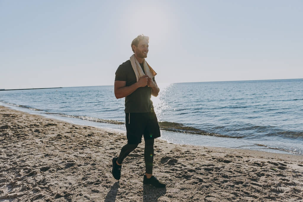 Happy man walks along beach on a sunny day