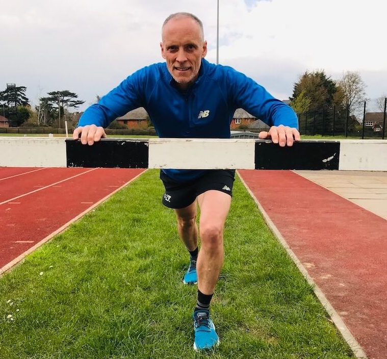 Kelsey Publishing CEO Steve Wright leans on a hurdle at a running track
