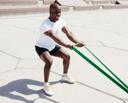 A man exercising outside with a resistance band