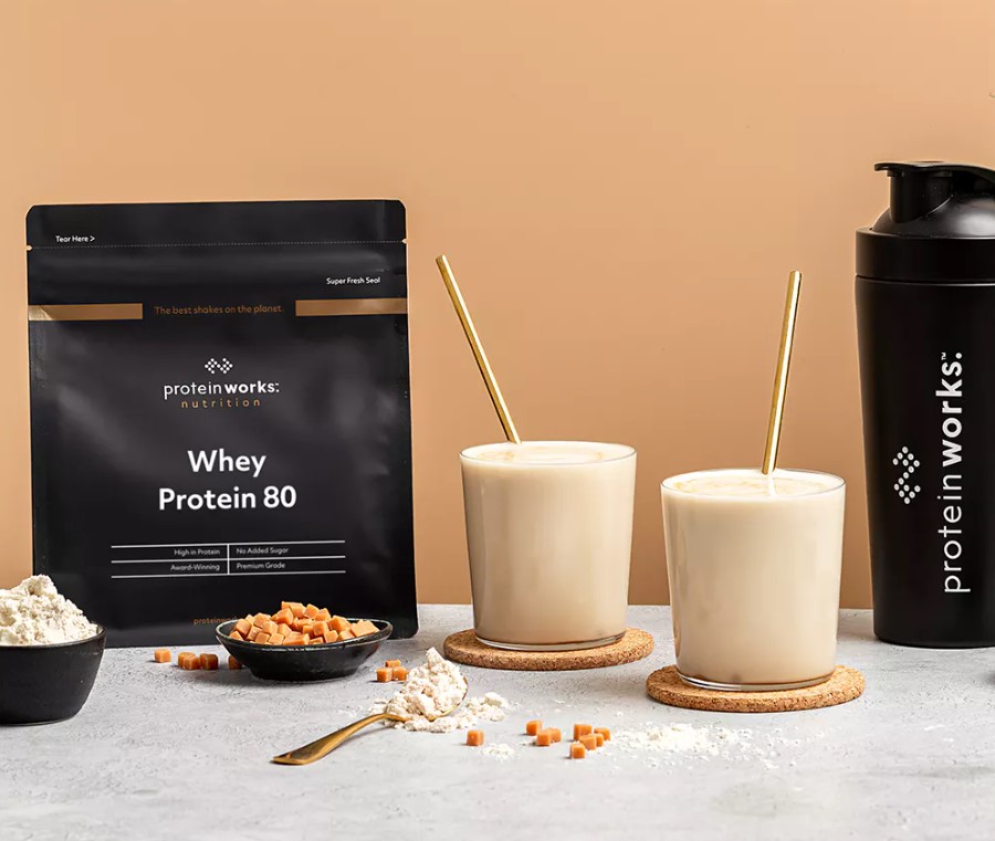Product shot of Protein Works sachets and two shakes with straws
