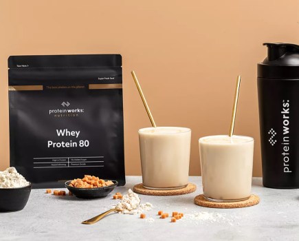 Product shot of Protein Works sachets and two shakes with straws