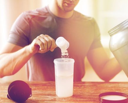 Man at a table measuring out a serving of whey protein powder