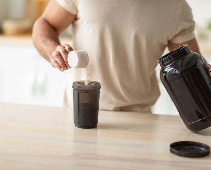 Mid-torso shot of a man at home making a pre-workout drink