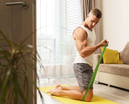 A man exercising at home with a resistance band